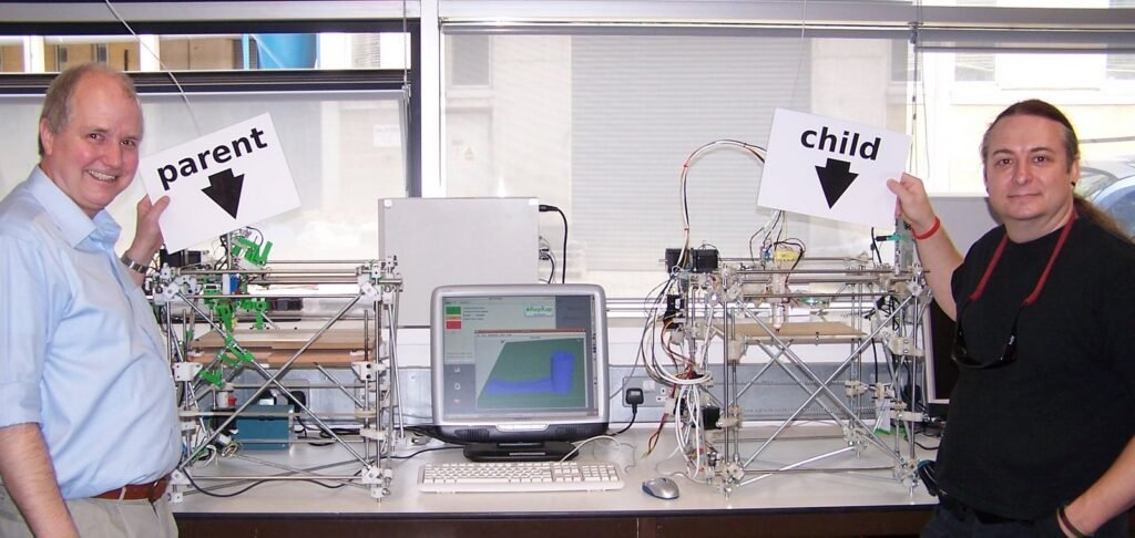 All of the plastic parts for the machine on the right were produced by the machine on the left. Adrian Bowyer (left) and Vik Olliver (right) are members of the RepRap project.